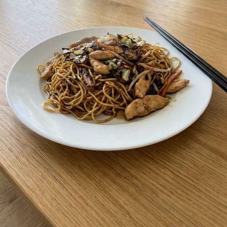 Chicken chow mein on a white plate with chopsticks, home kitchen